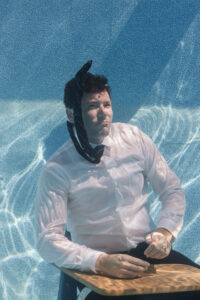 Neil Colvin Sits At a Desk In His Pool, Explaining How He Updates Addresses On Google Maps