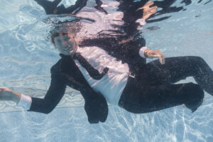 Advertising on Bing by Neil Colvin in a black suit while swimming in blue water.
